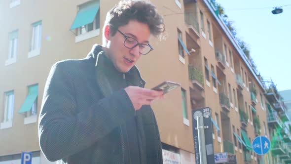 Young man outdoor using smart phone sending vocal message laughing