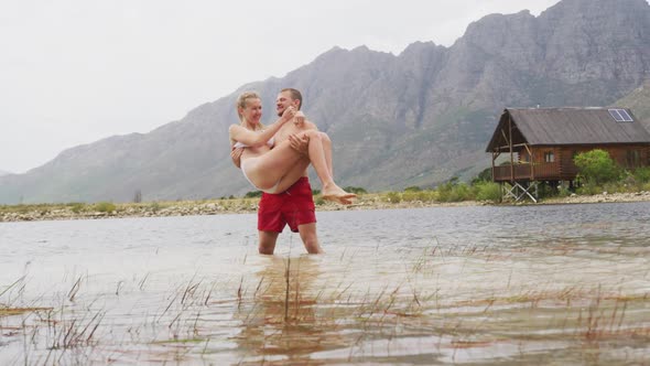 Caucasian couple having a good time on a trip to the mountains, wearing bathing suits and standing i