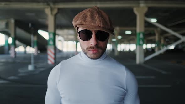 Young Serious Hipster Guy Is Looking at Camera During Posing at Summer Street Parking. Brutal Man