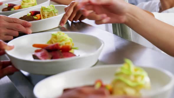 Team of chefs holding food dishes in commercial kitchen