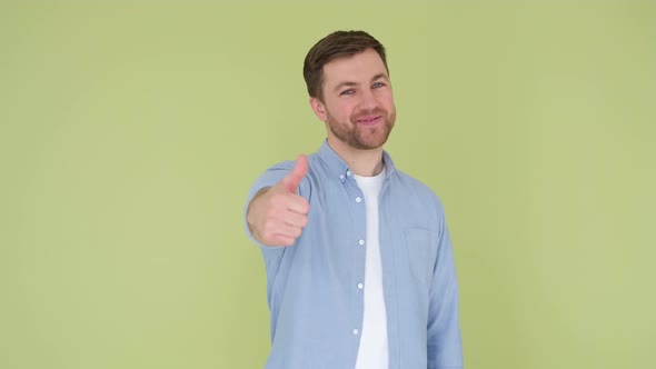 The Guy Shows His Thumb Up He is Wearing a Denim Shirt on an Olive Background