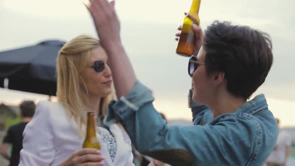 Smiling Women Having Fun, Drinking Beer And Dancing Outdoors.