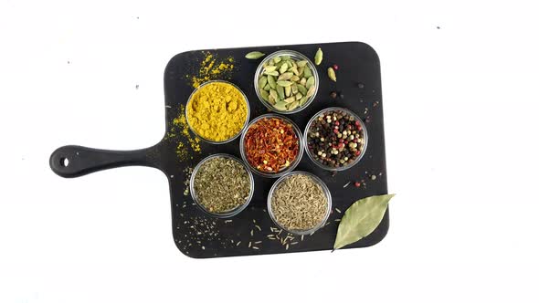 Different Indian Spices and Herbs Rotated on White Background in Glass Bowls