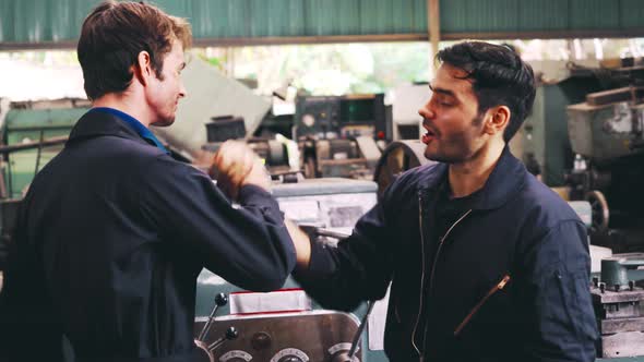 Tired Factory Workers Taking a Break and Talking to Coworker in the Factory