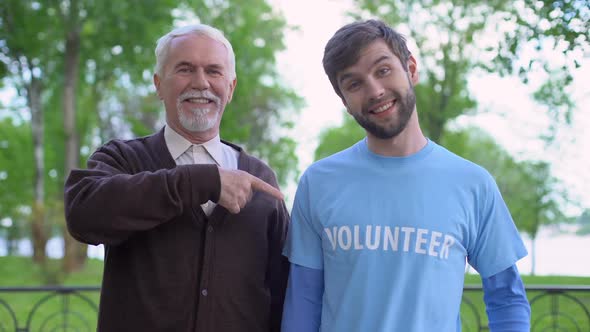 Male Pensioner and Social Activist Pointing at Volunteer Word on T-Shirt, Help