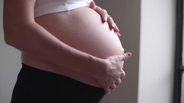 Close-up of pregnant woman rubbing her bare stomach