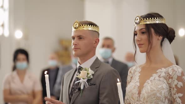 Newlyweds ceremony caucasian bride groom stand in church, holding candles in their hands