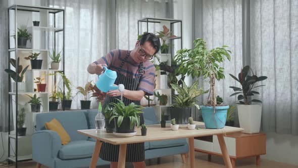 Asian Man Holding Watering Pot To Water The Plants At Home