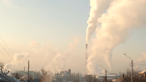 Smoke Streams Up Into the Sky From a Factory Chimney Above the City