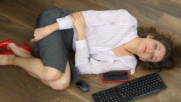 Tired Young Female Office Manager is Lying on the Floor with Keyboard Mouse and Smartphone Lay Flat
