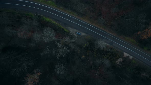 Top View Drone Rotating Directly Above Black Car Standing at Dark Dangerous Mystic Forest Road
