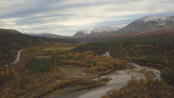 Areal mountain road and river. Drone camera tilts down.