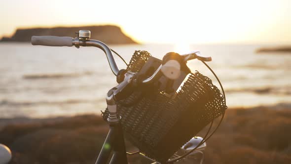 Closeup Basket on Bicycle Steering Wheel in Sunrays in Twilight