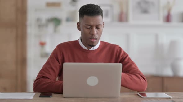 African Man Coughing while using Laptop in Office