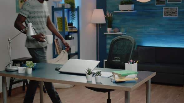 Black Man Working From Home with Laptop and Coffee at Desk