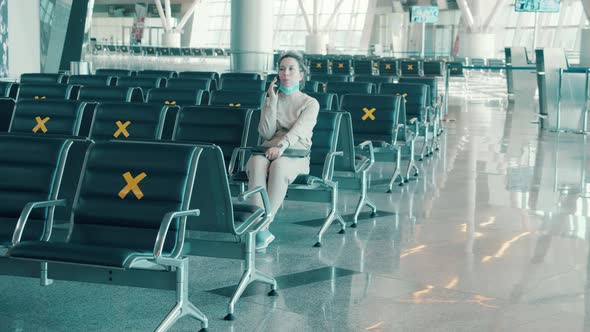 Woman is Talking on the Phone in the Empty Departure Lounge