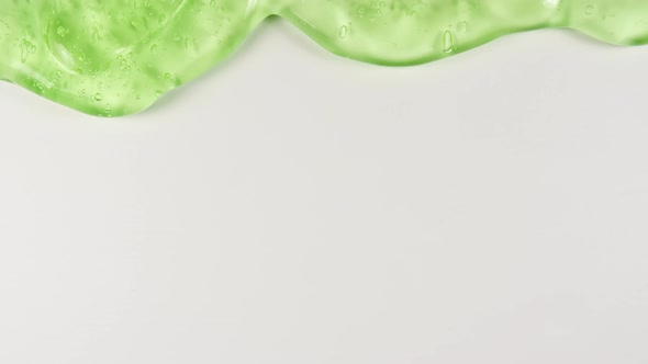 Green Transparent Cosmetic Gel Fluid With Molecule Bubbles Flowing On The Plain White Surface