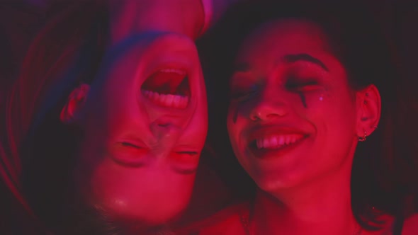 Two girls lying on the floor smiling and having intimacy moments