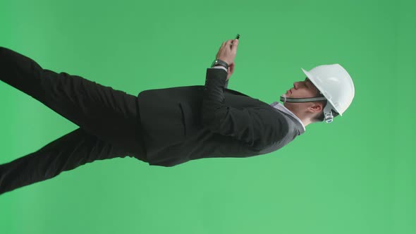 Asian Chief Engineer In The Hard Hat Use Mobile Phone While Walking On Green Screen Chroma Key