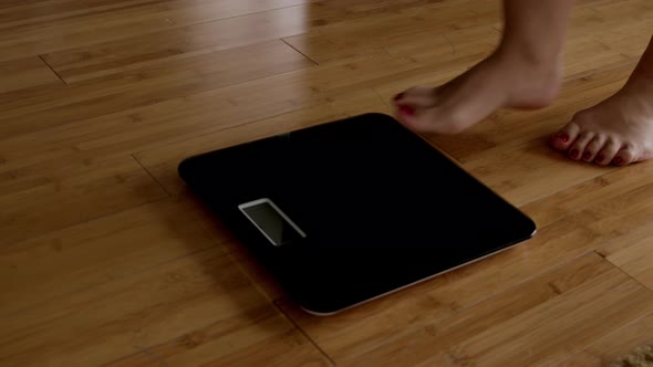 Woman is Measuring Her Weight on the Scales