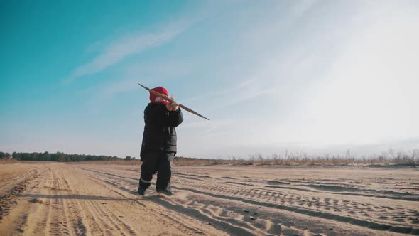 Happy Little Boy Playing with a Wooden Plane in Nature During Sunset. Kid Holds a Wooden Airplane