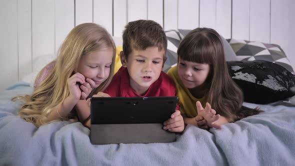 Happy Small Modern Friends in Multi Colored T-shirts Use a Tablet Computer and Communicate with Each