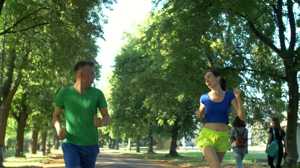 Cheerful Female Runner Overtake Man on Park Trail