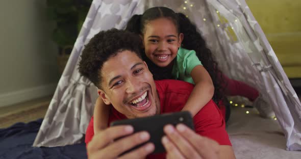 Happy biracial father and daughter using smartphone together