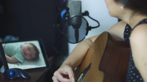 Slow Motion of Woman Playing Guitar Watching Baby Through Baby Monitor