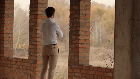 Businessman In White Shirt Standing In Unfinished House And Thinking. Man Watching To Horizon.