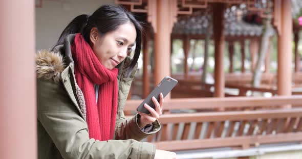 Woman use of smart phone in the chinese  pavilion garden