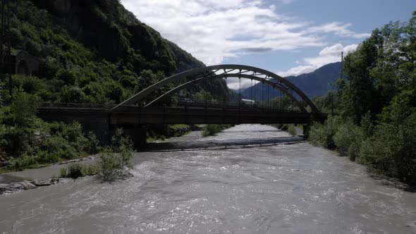 A truck and some cars driving over a bridge which is over a river with a lot of water because of a f