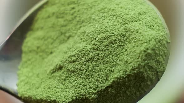 Slow Motion Macro of an Iron Spoon with Handful Matcha Being Poured Into Cup