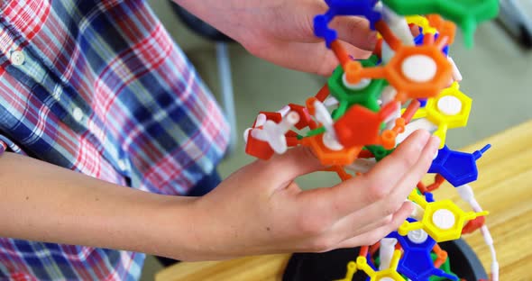 Schoolboy experimenting molecule model in laboratory at school