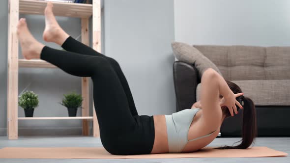 Athletic Female Training Abs Exercising Lifting Legs Lying on Mat at Home Enjoying Healthy Lifestyle