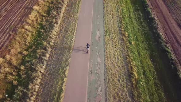 Top aerial view of a guy riding A Mountain Bike In The Road At Sunset During A Cold Autum