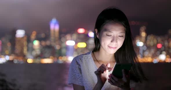 Woman use of mobile phone in city at night