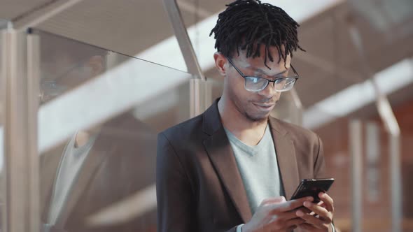 Young Black Businessman Texting on Smartphone in Office