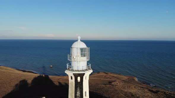 A Typical Striped Lighthouse on the Coast of the Steppe Area in the Evening. Seashore Steep Aerial