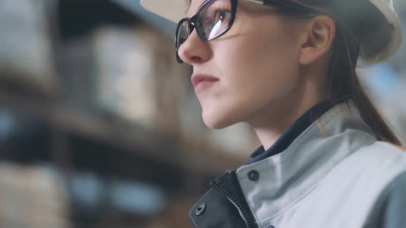 Attractive Female Warehouse Employee Wearing Grey Uniform and Hard Hat