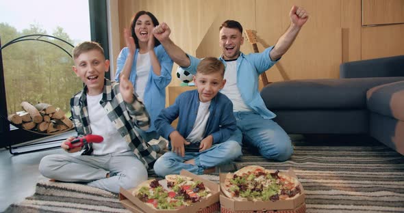 Emotional Smiling Parents Celebrating Children's Victory in Video Game in Living-Room 