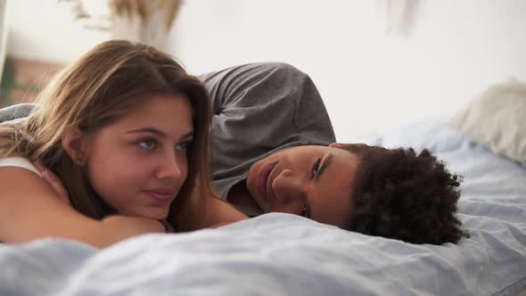 Closeup View of Happy Multiracial Couple Lying in Bed and Talking