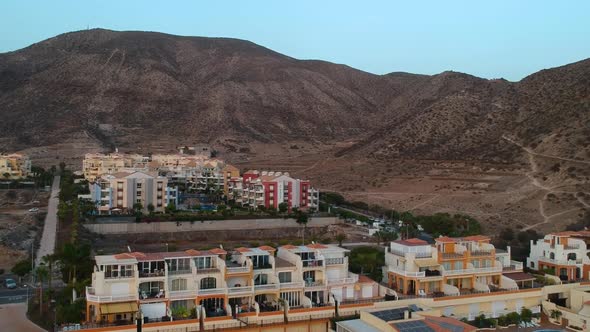 Colorful resort buildings with balconies in Tenerife island with mountain behind, aerial view