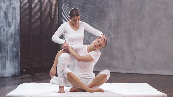 Young woman is getting Thai massage treatment by professional therapist.