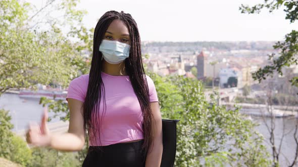 A Young Black Woman in a Face Mask Shows a Thumb Down To the Camera and Shakes Her Head