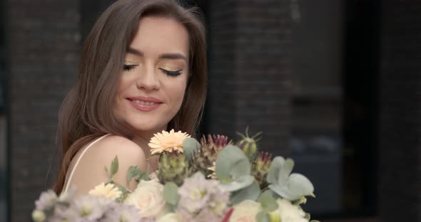 Happy Elegant Young Woman with Flowers in the City