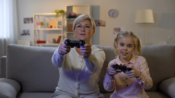 Cute Girl and Modern Granny Playing Video Game at Home With Joysticks, Leisure
