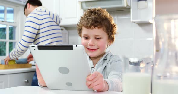 Father talking on mobile phone while son using digital tablet