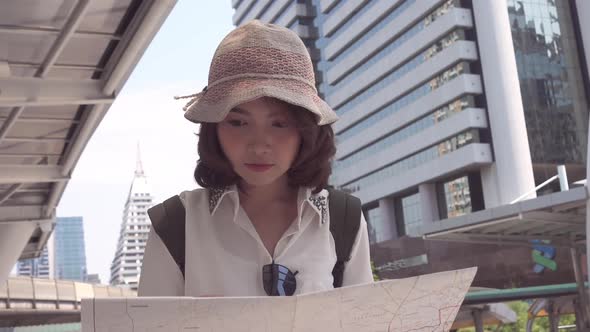 young Asian backpacker woman direction and looking on location map while traveling