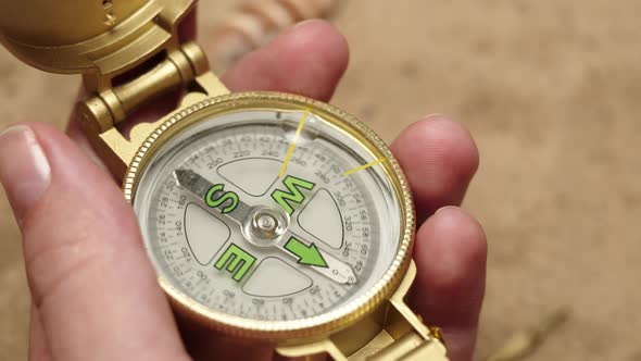 Man Hand Holding Gold Compass on Sand Background Closeup Golden Compass in Human Palm